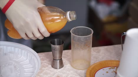 pouring orange juice into a cocktail shaker