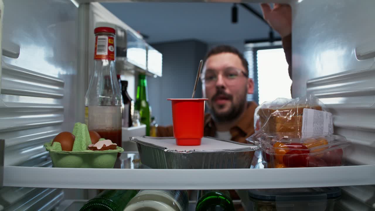 음식과 함께 냉장고 안과 안을 바라보는 사람