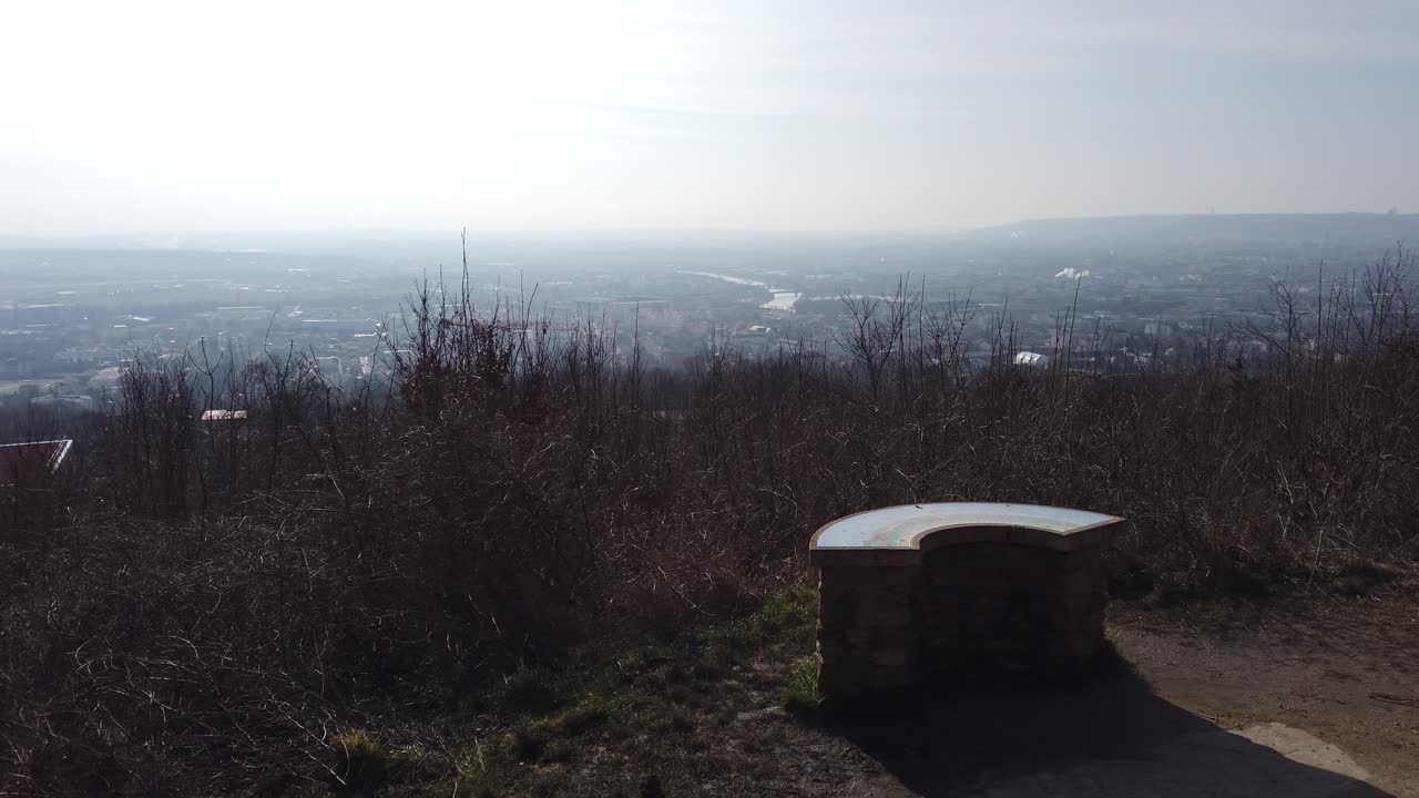 A serene landscape view from Plateau de Malzéville, overlooking the expansive cityscape below, with a clear sky and natural surroundings.