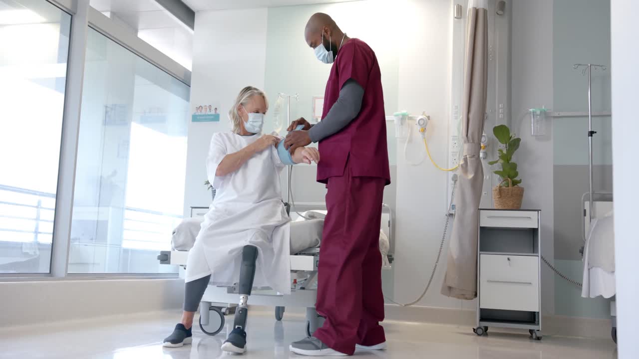 médico afroamericano controlando la presión arterial de una paciente caucásica en el hospital
