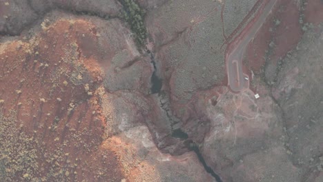 aerial orbit shot over big canyon in karijini national park with large gorge and stream in western australia