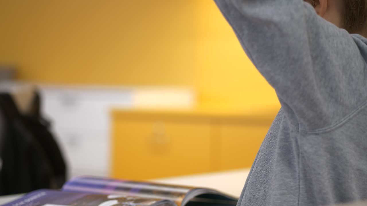 joven colegial blanco levantando la mano, de cerca