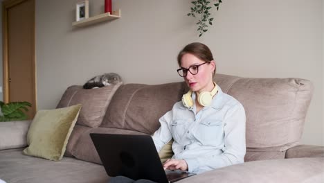 Woman working on laptop at home with cat