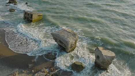 hermosa vista aérea de la costa de karosta, ruinas de la fortificación de hormigón, noche soleada de verano, luz de la hora dorada, olas tormentosas en el mar báltico, cámara lenta de un dron que avanza