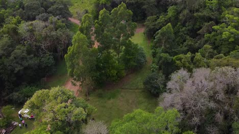 Drone-Shot-Argentina-Pueblo-De-Santa-Ana-Con-Gente-En-Las-Calles-Bosque-Con-Mediodía-Por-La-Tarde-Con-Cielo-Azul-Paisaje-Nublado-Alrededor-De-La-Casa-De-Santa-Ana-En-El-Bosque