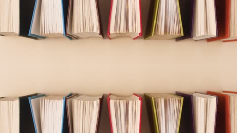 vintage hardcover books appear on top and bottom of beige background with copy space. stop motion flat lay