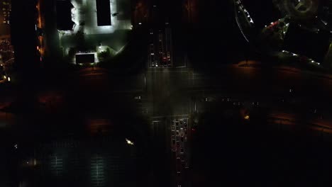 over head clip of a intersection at night with cars turning through it