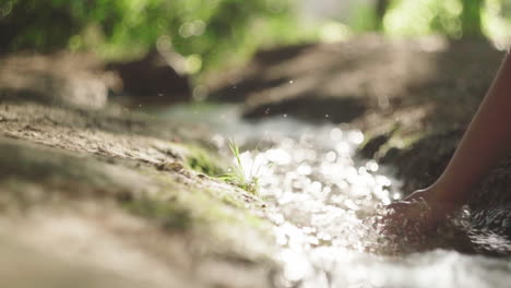 crop woman touching flowing water in river at night