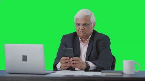 Angry-Indian-senior-manager-using-mobile-phone-Green-screen