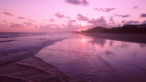 stunning establishing aerial shot of waves and beach with pink sunset, brazil