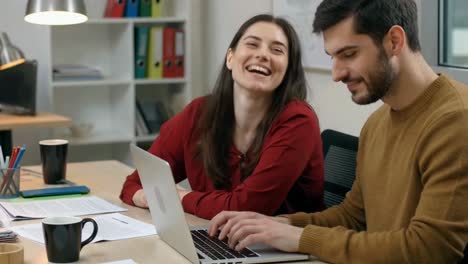 colleagues collaborating on laptop in modern office setting