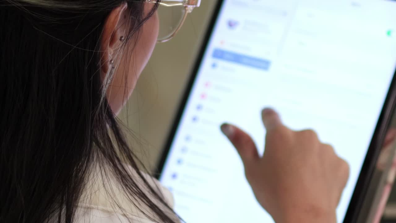 A woman uses a tablet, navigating through digital content with precision and focus.