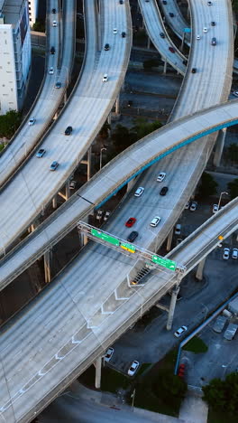 intertwining freeways with cars moving by. two motor boats sail by the river in miami under drawbridge. top view. vertical video