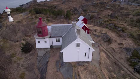 aerial orbiting view of an old lighthouse on a rocky outcropping near the village of sorvagen in lofoten norway in late winter