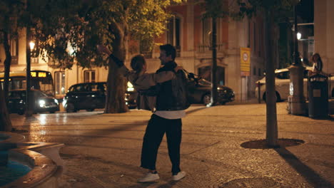 hombre feliz girando chica con las manos en la calle de la ciudad. amantes despreocupados en la fecha