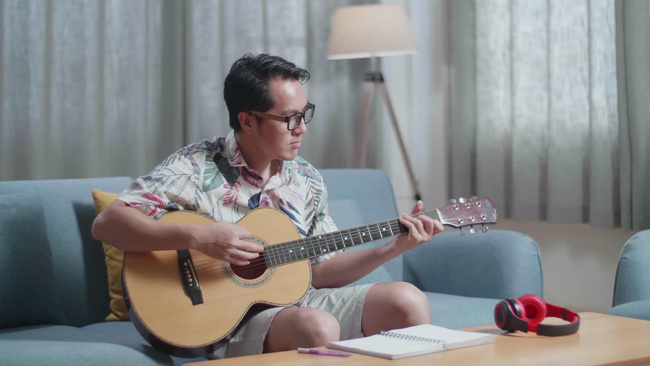 집에서 기타를 연주하는 테이블 위에 노트북을 가진 아시아인 작곡가