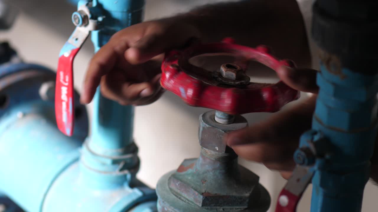 펌프실에서 큰 빨간색 값을 돌리는 인간의 손