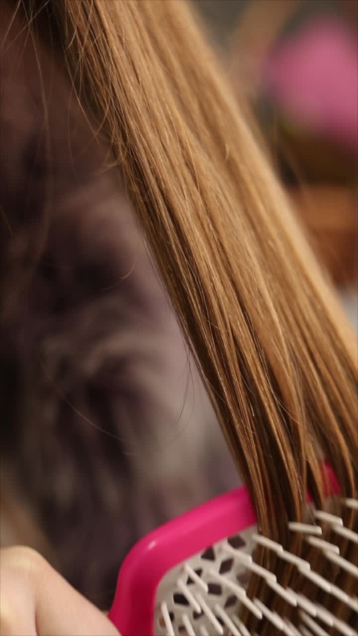 Woman brushing her hair with a pink hairbrush