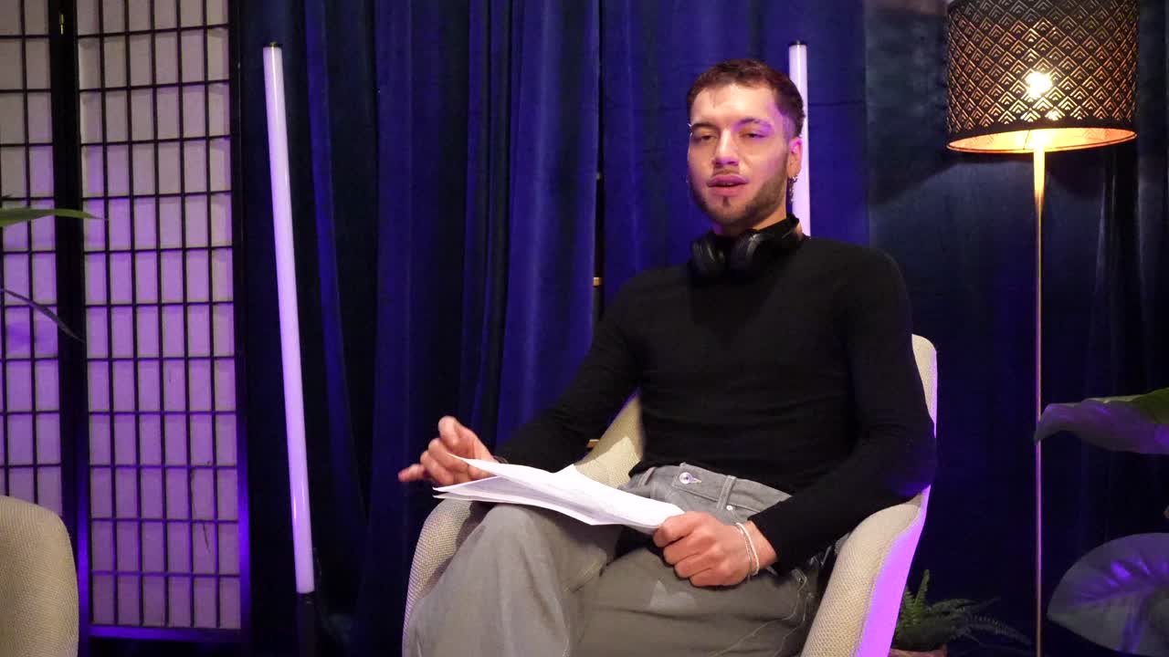 Giovane uomo che parla e gesticola in un moderno studio.