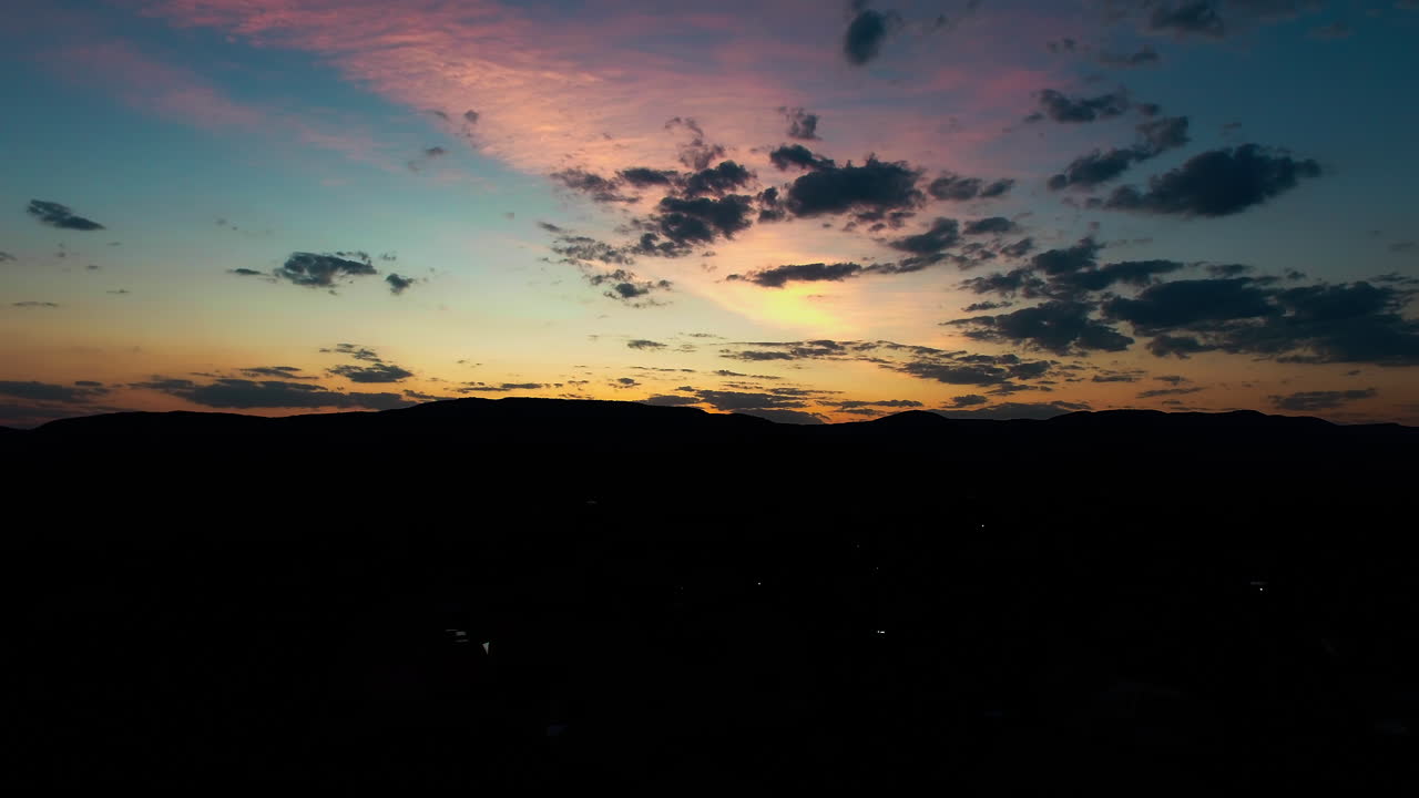 The sky in it's magnificent rainbow colors. Golden hour sunset. Time lapse moving backwards with clouds that follow. Blue skies with dark clouds - a tint of magenta color. Day to night time lapse.