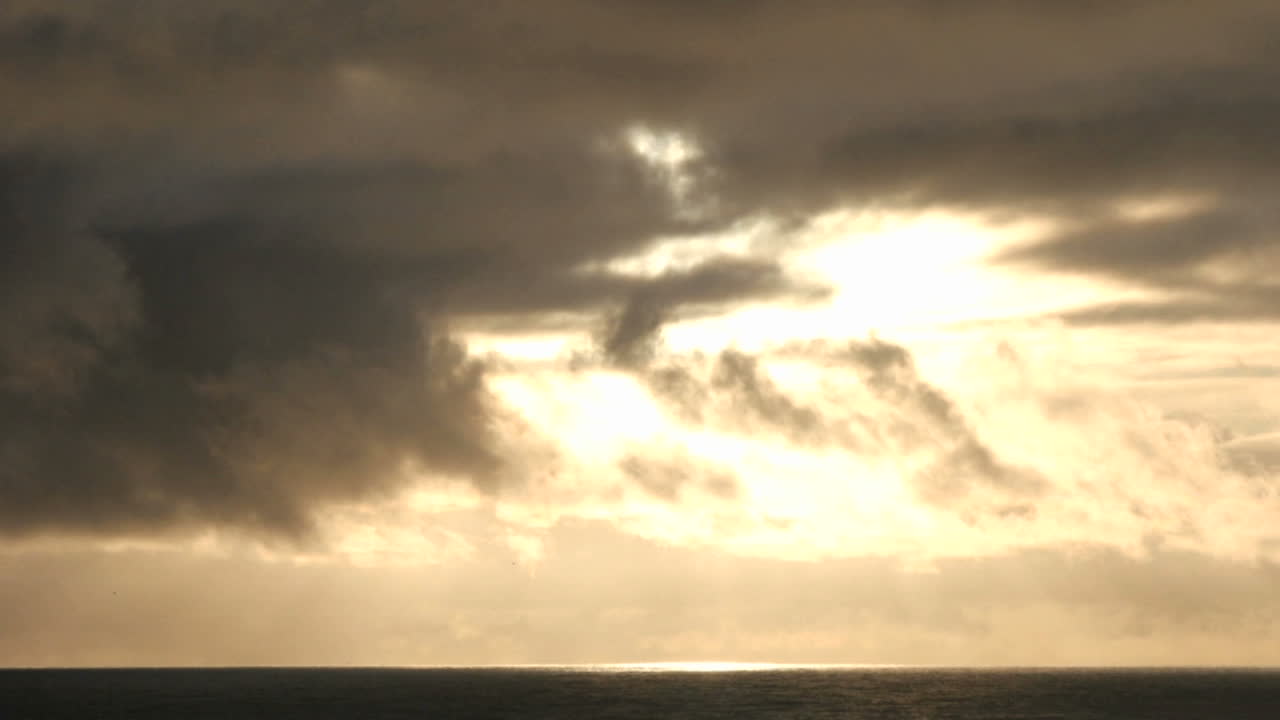 구름이 어두워지는 하늘에서 태양 위로 빠르게 움직입니다.