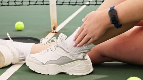 woman with injured ankle on tennis court
