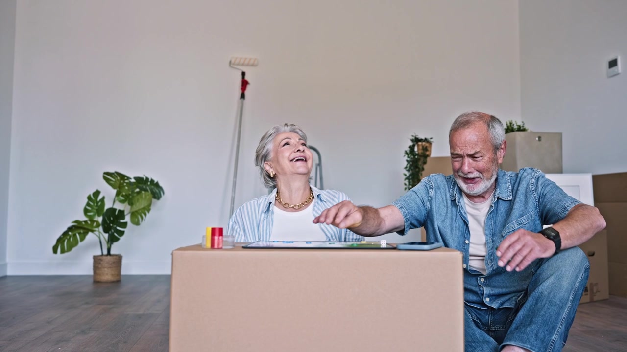 Šťastný seniorský pár hraje deskovou hru ve svém novém domově