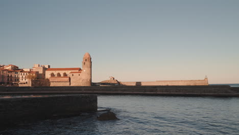 Ruhige-Uferpromenade-Von-Collioure,-Im-Hintergrund-Die-Majestätische-Kirche-Notre-Dame