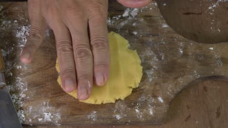 la mano de la mujer chef está aplanando la masa de galletas en la tabla de corte de madera vista superior