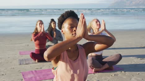 grupo de diversas amigas meditando en la playa