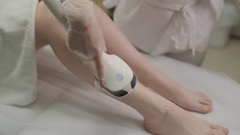 laser epilation and cosmetology in beauty salon. cosmetology, spa and hair removal concept. laser hair removal procedure of female legs. doctor in gloves.