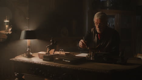 old passionate man writes down a note in his office at night