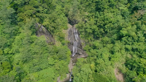 dolly out aerial shot of a small waterfall in the middle of a mountain