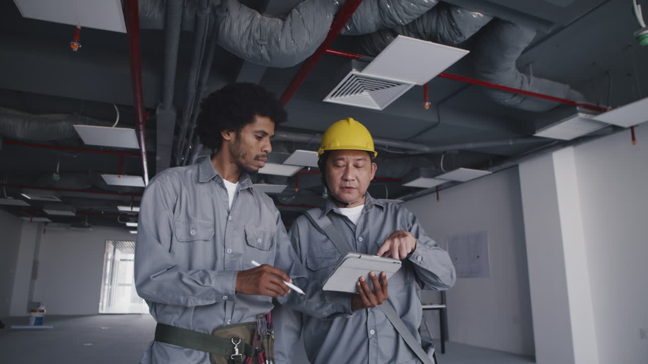 Diverse Builders Looking at Blueprint on Tablet at Construction Space