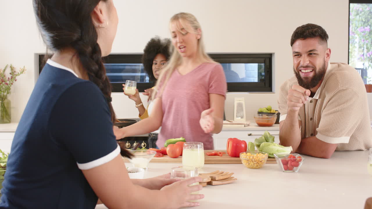 Cooking together, young friends laughing and preparing meal in modern kitchen