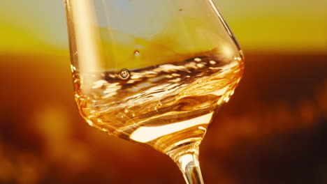 orange or white wine bottle and glass against a sunset in a peaceful vineyard, pouring of ecological natural wine.