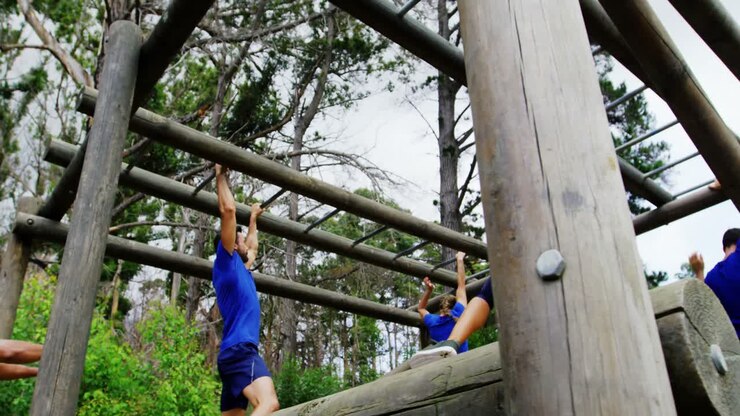 Female trainer clapping hands while fit people climbing monkey bars 4k