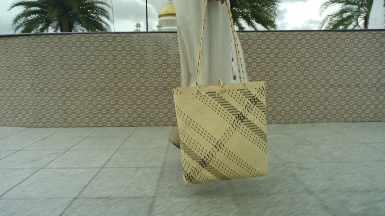 hermosa joven asiática con bolsa natural caminando por el pavimento cerca de la fuente