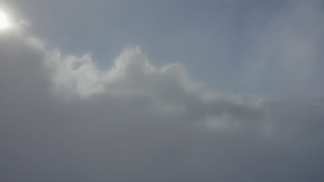 aerial dolly view through white clouds at daylight below a blue heaven