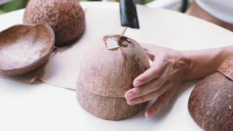 cerrar la vista superior de las manos femeninas cubriendo una cáscara de coco con aceite