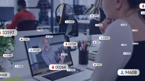 animación de iconos de las redes sociales contra una mujer caucásica haciendo una videollamada en una computadora portátil en la oficina