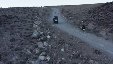 dirt bike cruising up gravel road in rocky desert landscape