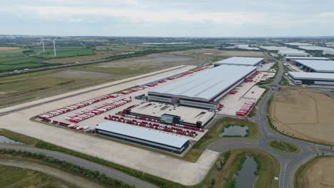 aerial drone cinematic orbit footage of freight warehouse and industrial storage distribution facility with trucks near lutterworth england uk