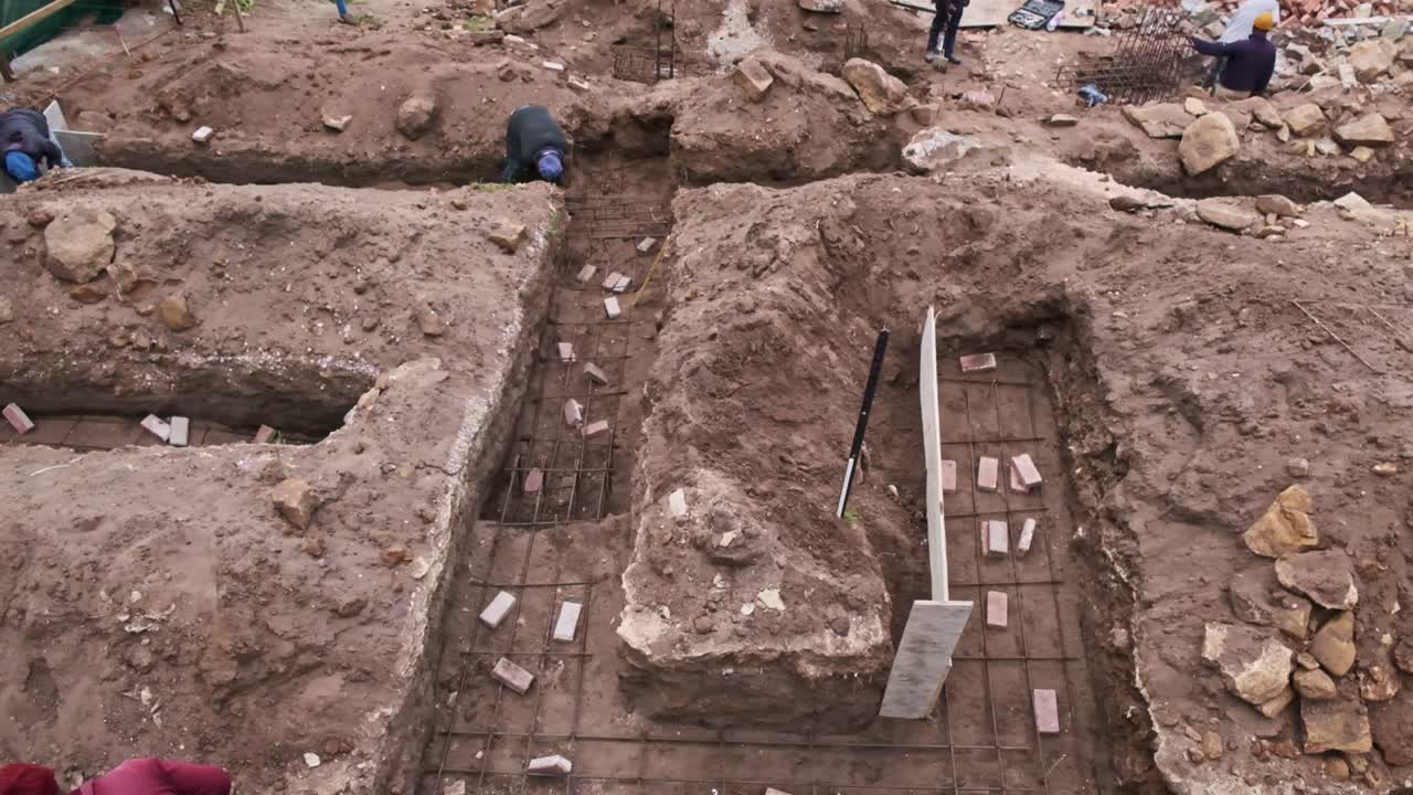 Trenches for a house foundation being excavated on a building site near a river with steel reinforcement