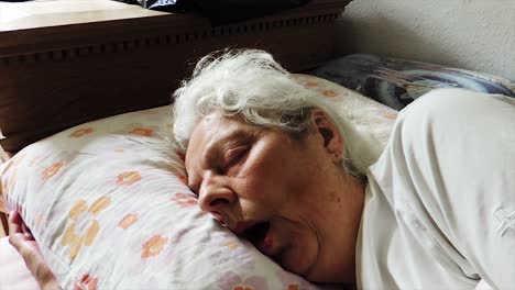 anciana cansada durmiendo en la cama - disparo constante de mano