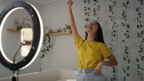 adolescente caucásica bailando y grabando un video para las redes sociales usando luz de anillo