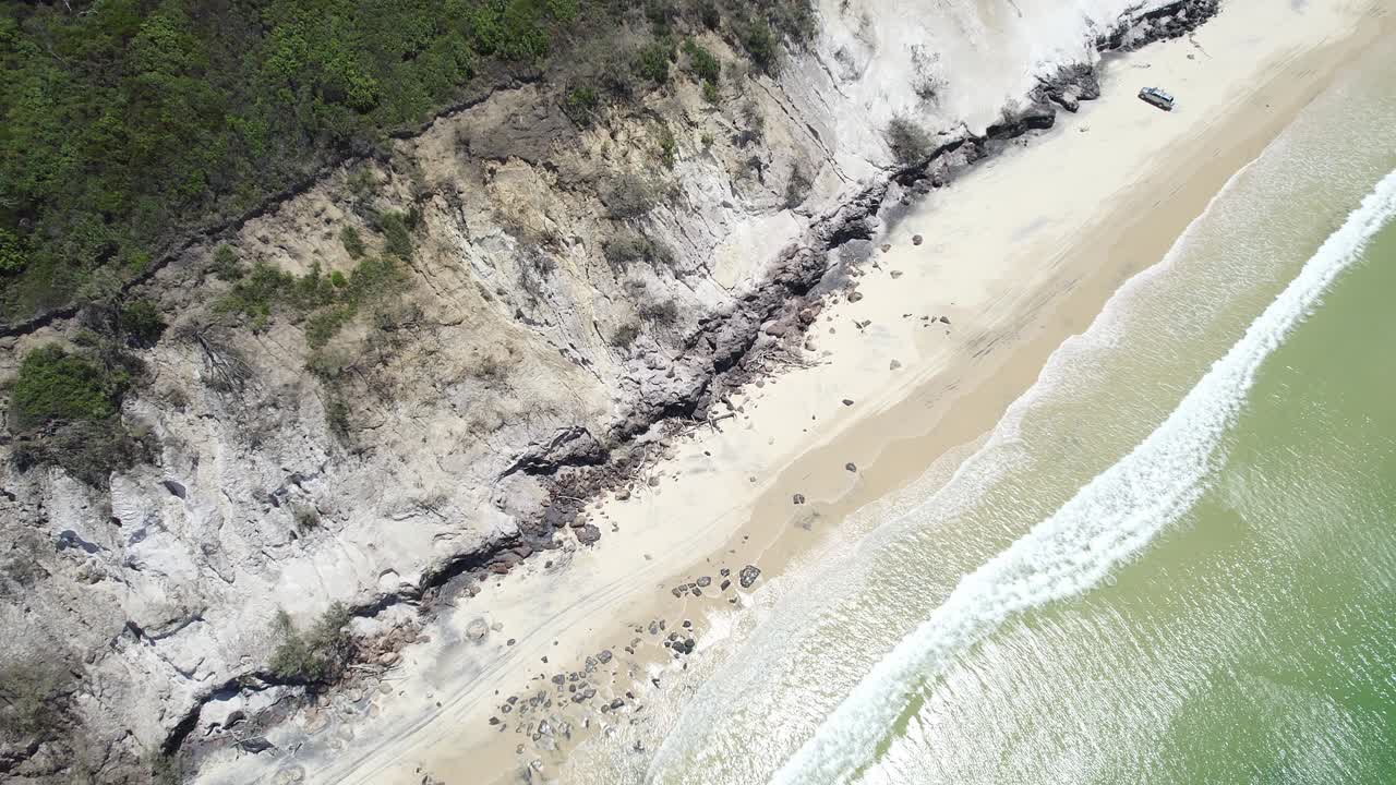 olas rompiendo en la playa de arena con un vehículo estacionado en verano