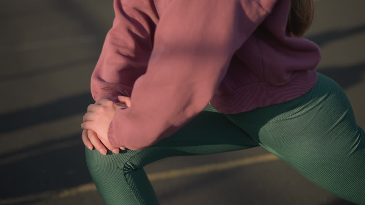 joven realizando ejercicios de acondicionamiento físico arrodillado hacia adelante, sombras proyectadas en el suelo que destacan el movimiento, creando una atmósfera de entrenamiento dinámica y enfocada en un entorno al aire libre