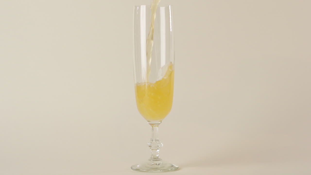 Pouring sparkling wine in achampagne glass in 100 FPS on white background