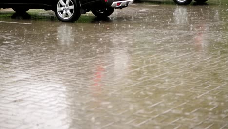 cars are wetted in parking lot in the city, there is heavy rain, torrential downpour, the whole parking lot is flooded with water, large drops fall with splashes into puddles